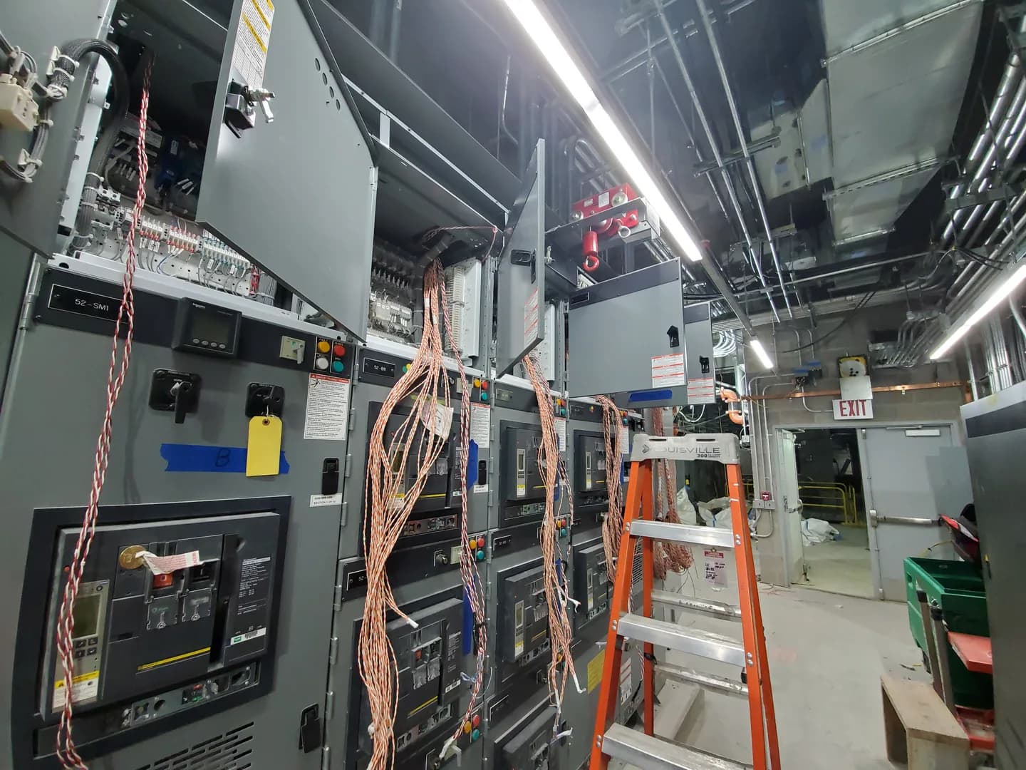 Cubículos abertos com fiação de controle acessível durante testes do sistema SCADA em subestação de Queens