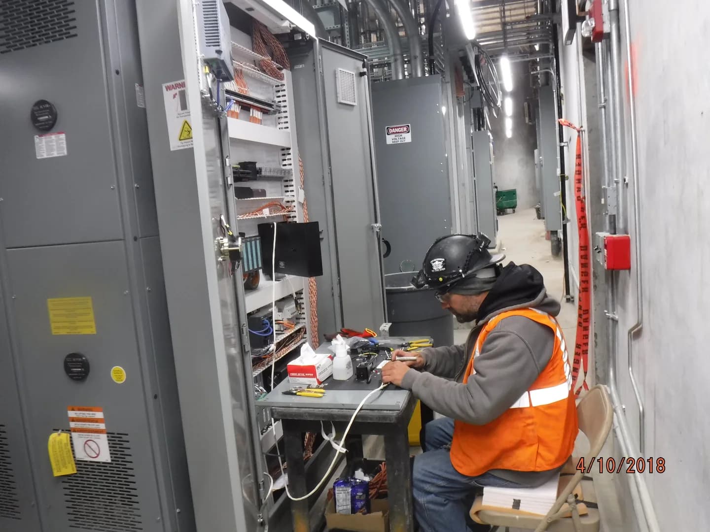 Técnico preparando conexões de fibra óptica junto a um armário de controle na subestação B11